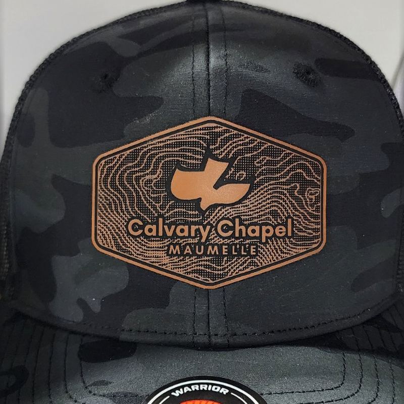 Black camo trucker hat with a rust hexagon patch engraved with topographic lines and Calvary Chapel Maumelle