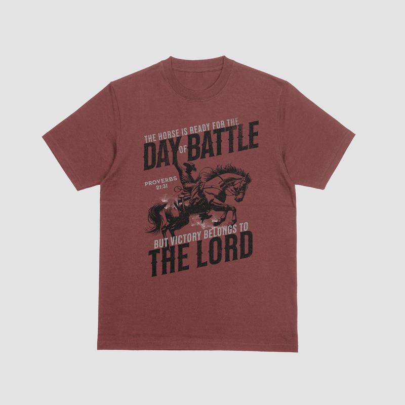 Brick red tee with a Proverbs 21:31 'Day of Battle — victory belongs to the Lord' horse and rider design (mockup)