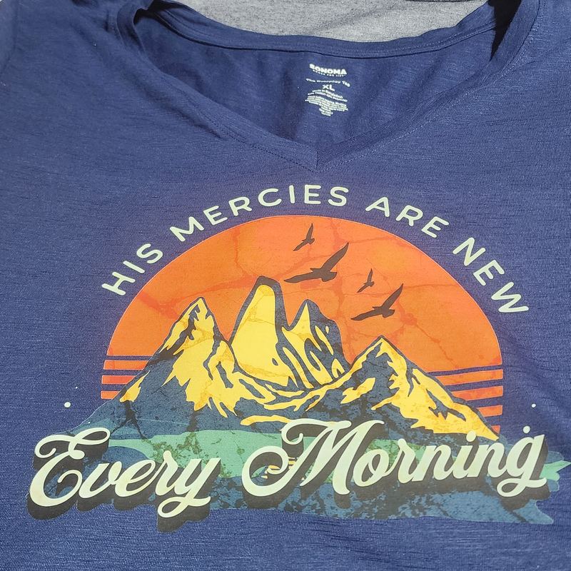 Navy V-neck tee with a mountain sunset design reading 'His mercies are new every morning'