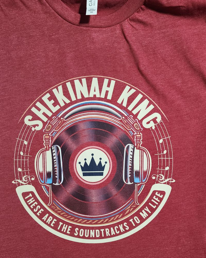 Heather red tee with a vinyl record and headphones design reading 'Shekinah King — these are the soundtracks to my life'